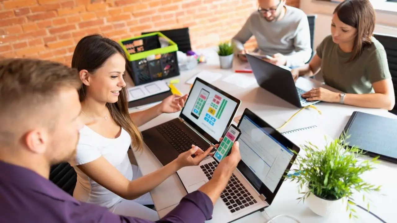 Team collaborating on mobile and laptop screens for small business website design australia.